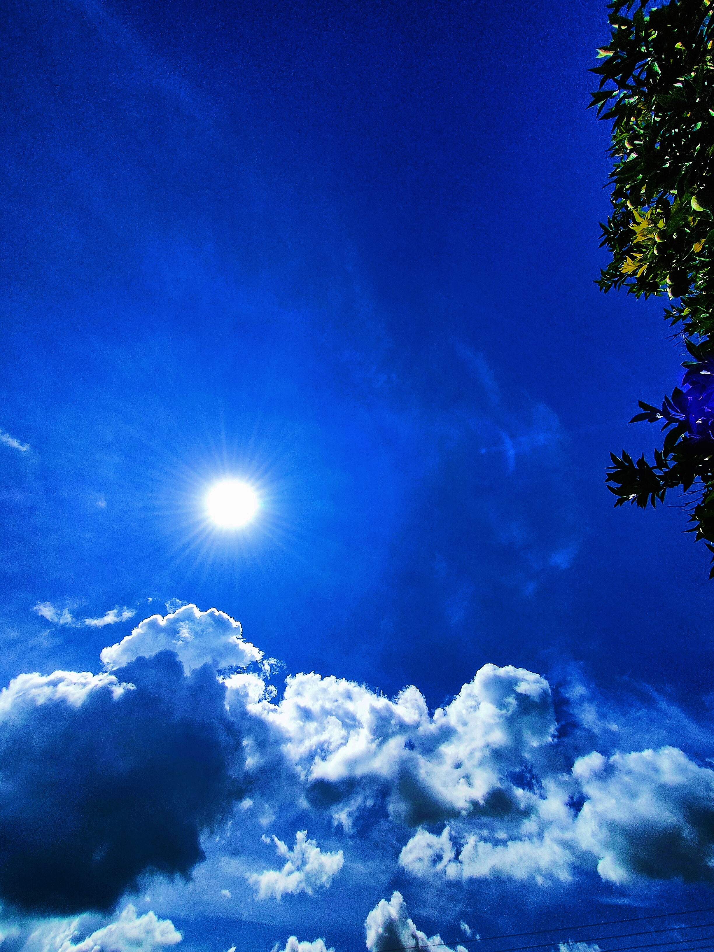 A radiant sun shines brilliantly in a clear blue sky, castin